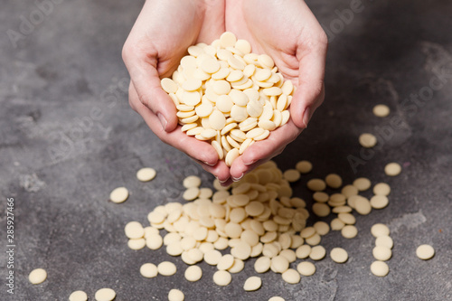 White chocolate chips in hands photo