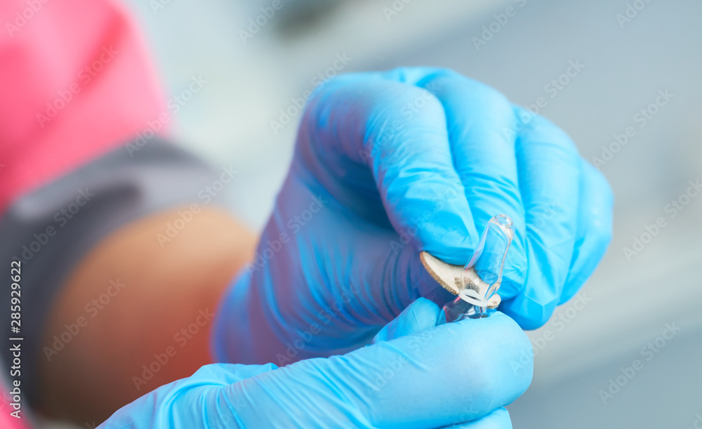 Fototapeta premium Close-up hands of young woman doctor anesthesiologist dressed in pink gown, blue gloves prepares solution for anesthesia in the operating room before the surgery.