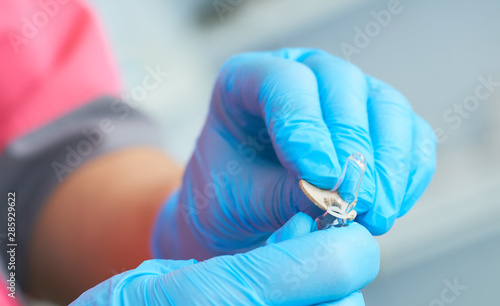 Close-up hands of young woman doctor anesthesiologist dressed in pink gown, blue gloves prepares solution for anesthesia in the operating room before the surgery.