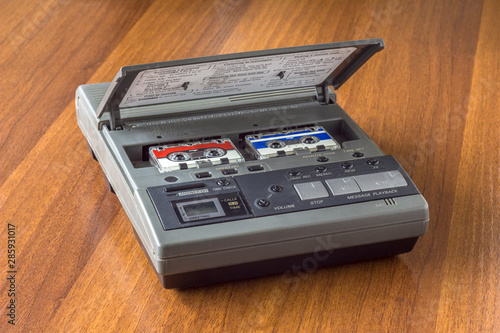old vintage answering machine with two small tape cassettes on a wooden table surface