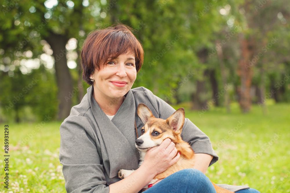 Portrait of cute happy mature woman with puppy dog pet in summer park Portrait of cute happy mature woman with puppy dog pet in summer park