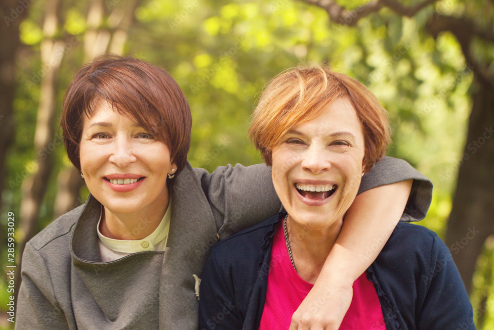Two happy women walking in summer park, portrait Two happy women walking in summer park, portrait