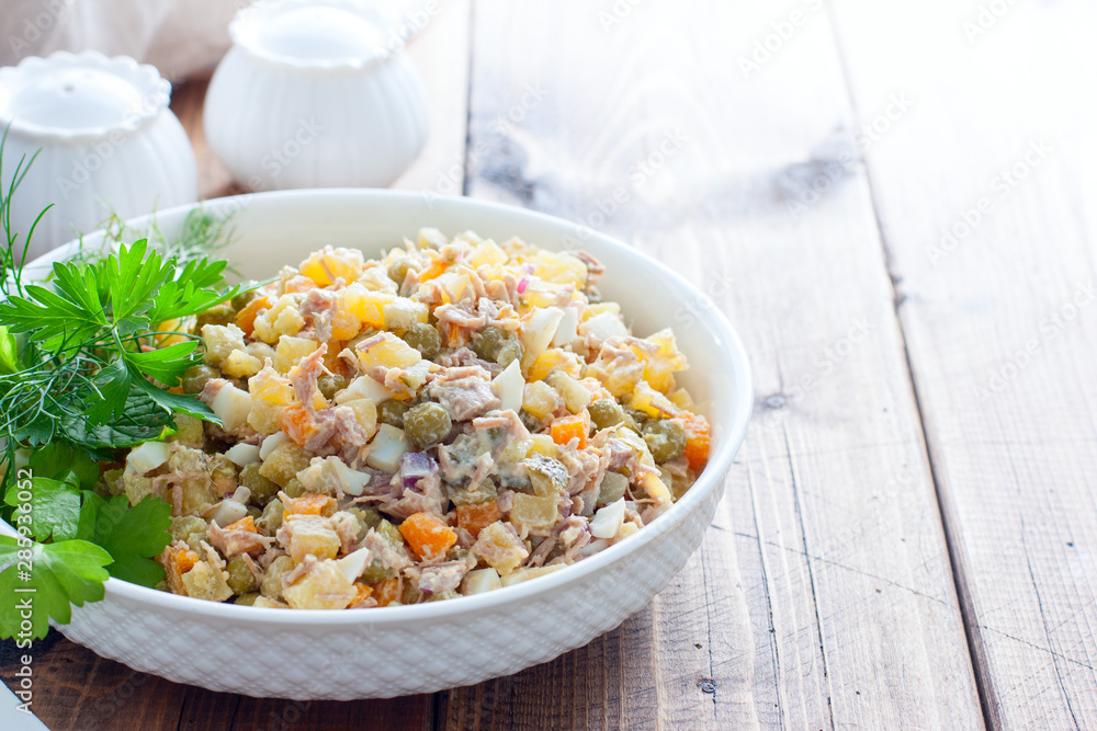 Olivier salad with boiled meat and meat on a wooden table, horizontal, place for text Olivier salad with boiled meat and meat on a wooden table, horizontal, place for text