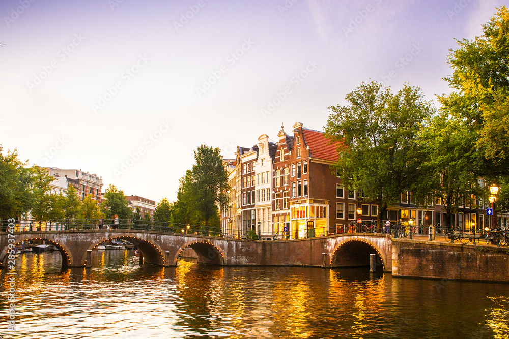 Obraz premium Amsterdam seen in the evening with light, canal and bridge