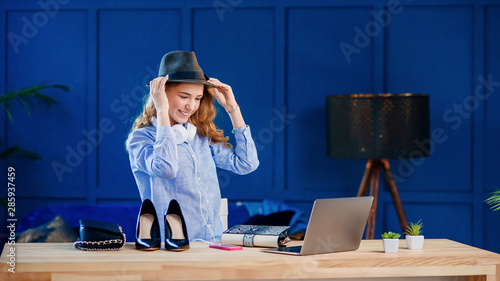 An attractive caucasian female blogger tries on a stylish hat while recording a blog video. photo