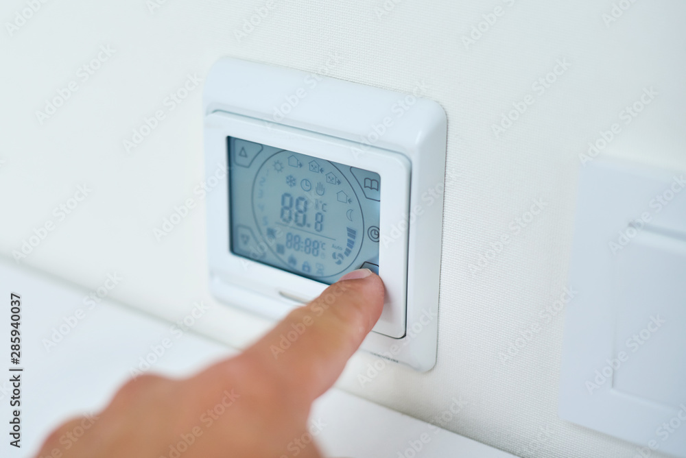Men hand setting temperature on the underfloor heating control panel Men hand setting temperature on the underfloor heating control panel