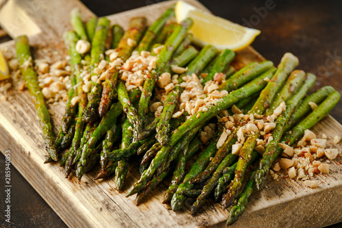 Fried asparagus tips served with crispy crushed peanuts on wooden board