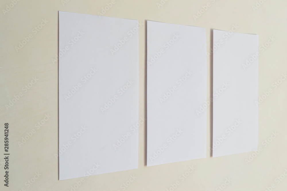 Three sheets of white paper on a beige wall. Three sheets of white paper on a beige wall.