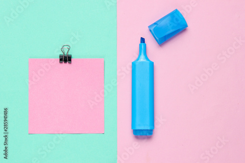 Stationery office supplies. Paper clip, felt-tip pen, memo piece of paper on pink blue pastel the background