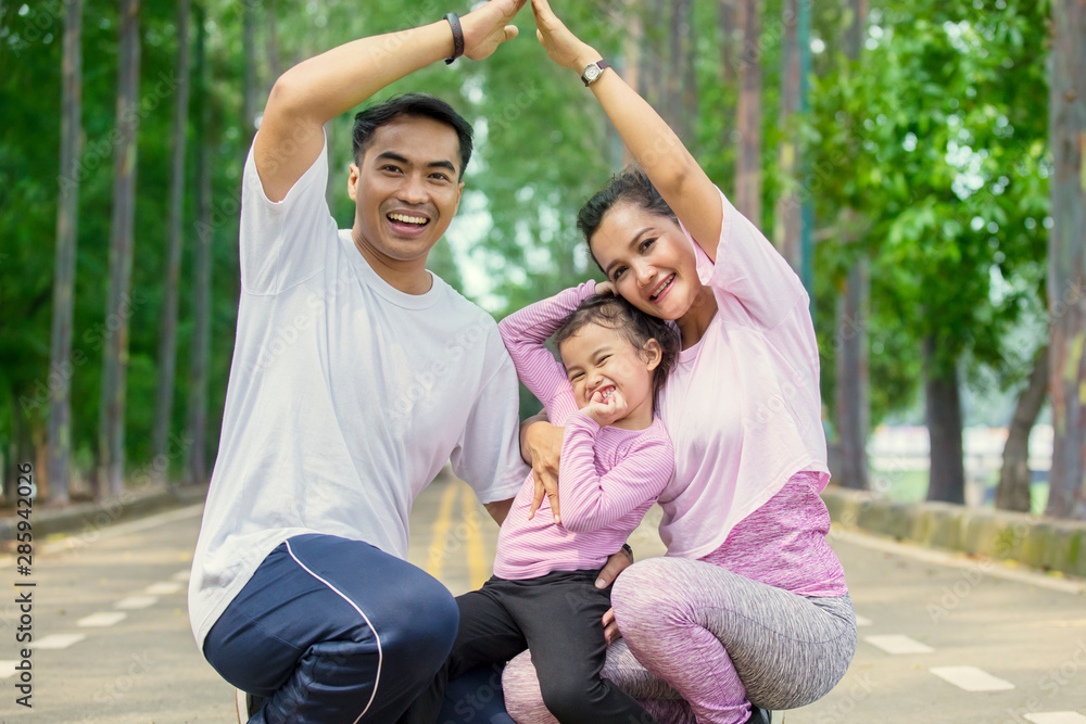 Cheerful family making house symbol in the park Cheerful family making house symbol in the park