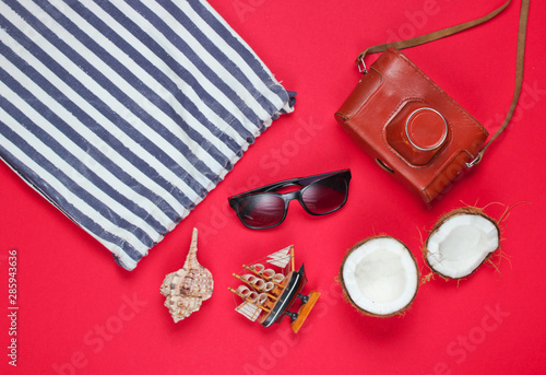 Summer creative background. Beach striped bag, accessories on red background. Top view. Flat lay