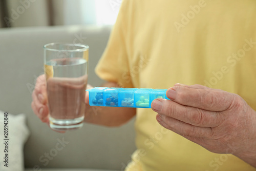 Elderly man with pills and glass of water in nursing home, closeup. Assisting senior people © New Africa