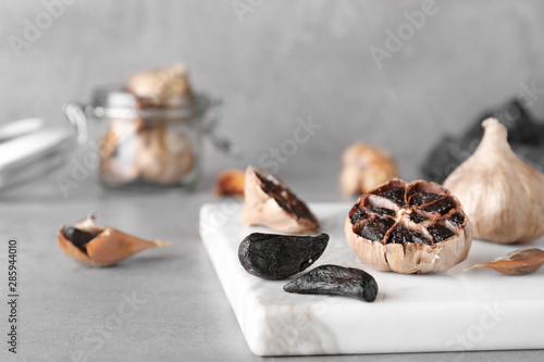 Marble board with black garlic on grey table. Space for text photo