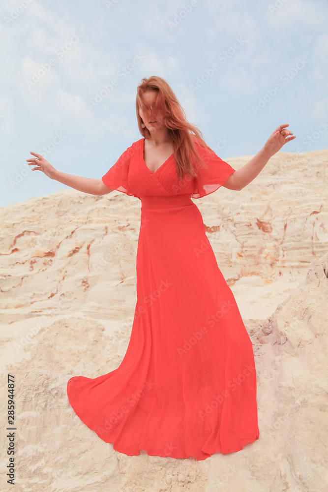 Young beautiful Caucasian girl stands on the mound of sand and looks down Young beautiful Caucasian girl stands on the mound of sand and looks down