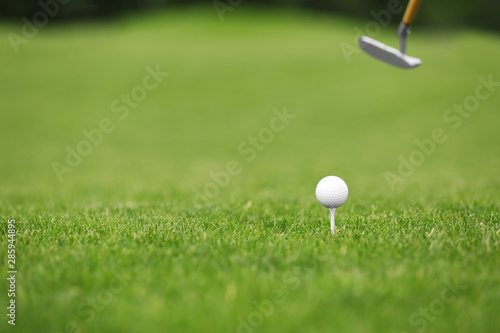 Hitting golf ball with club on green course. Space for text