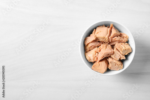 Bilde på lerret Bowl with canned tuna on light table, top view. Space for text