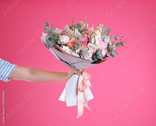 Man holding beautiful flower bouquet on pink background, closeup. Space for text photo