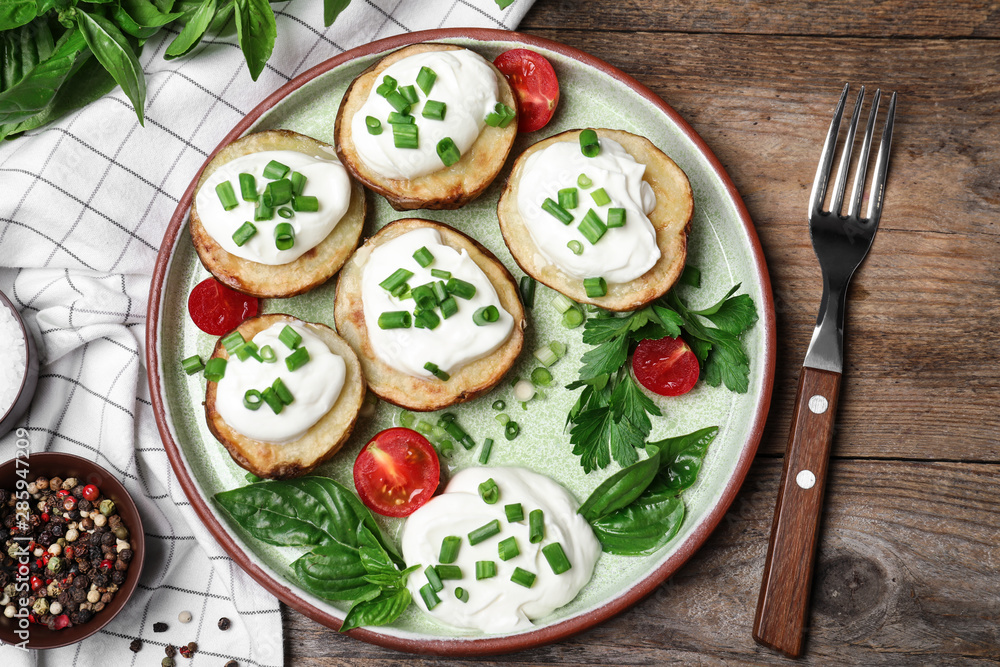 Delicious potato wedges with sour cream served on wooden table, flat lay Delicious potato wedges with sour cream served on wooden table, flat lay