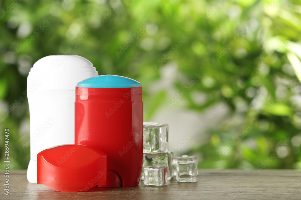 Obraz premium Different deodorants and ice cubes on wooden table against blurred background. Space for text