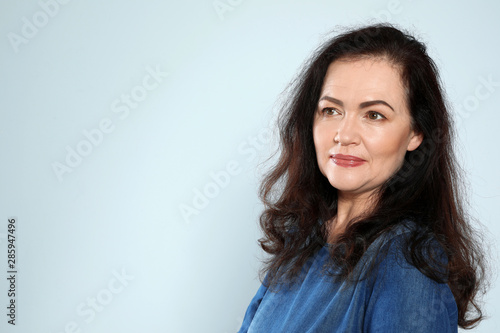 Portrait of mature woman with beautiful face on grey background. Space for text