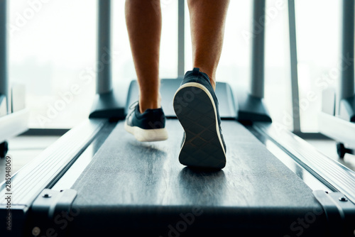 Wallpaper Mural Close up male muscular feet in sneakers running on the treadmill at gym