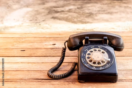Obraz Retro obrotowy czarny telefon na drewno stołu tle. Stary telefon z tarczą obrotową.
