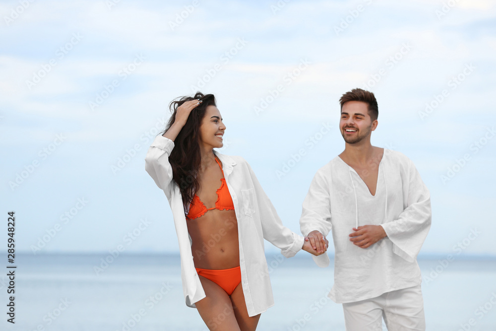 Happy young couple walking together on beach