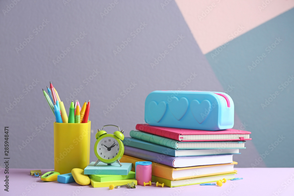 Fototapeta premium Different school stationery on table against color background