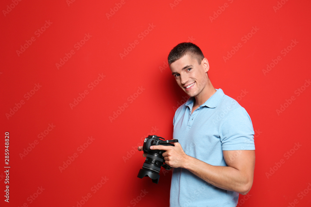 Young photographer with professional camera on red background. Space for text Young photographer with professional camera on red background. Space for text