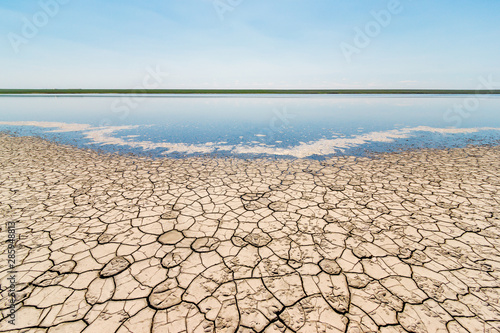 The coast of the salt lake with cracked dry ground and blue sky Fototapeta