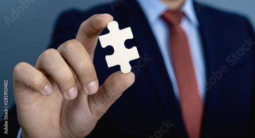 Businessman holds a piece of the puzzle  business concept © SZ Photos