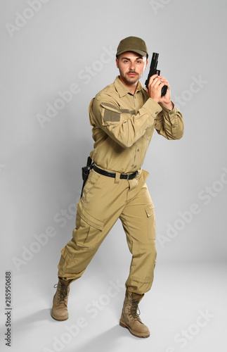 Male security guard in uniform with gun on grey background