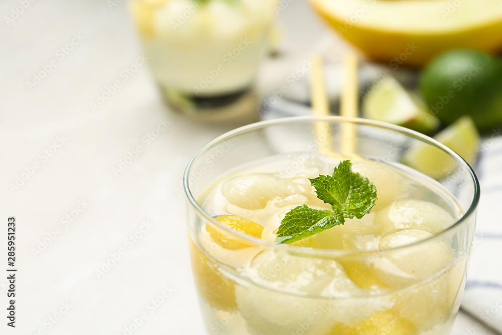 Glass of melon ball cocktail with mint on table, closeup