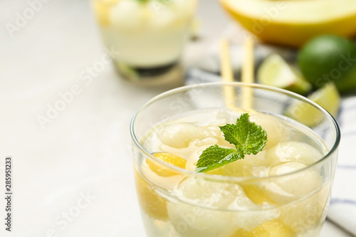 Glass of melon ball cocktail with mint on table, closeup
