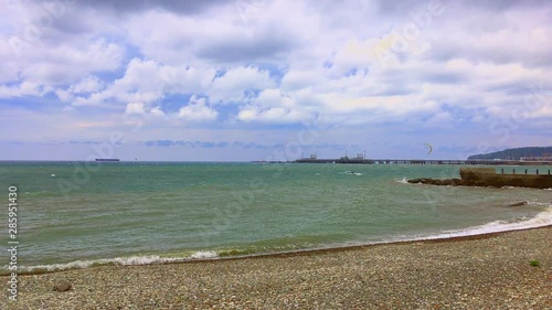Kitesurfers ride on the waves of a stormy sea in cloudy windy weather on a sunny summer day.