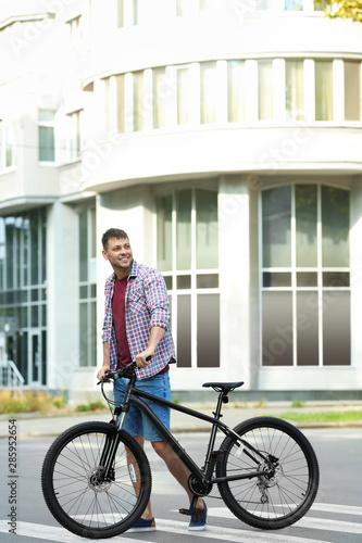 Handsome man with modern bicycle on city street