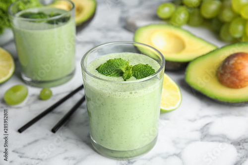 Glasses of tasty avocado smoothie with mint on marble table
