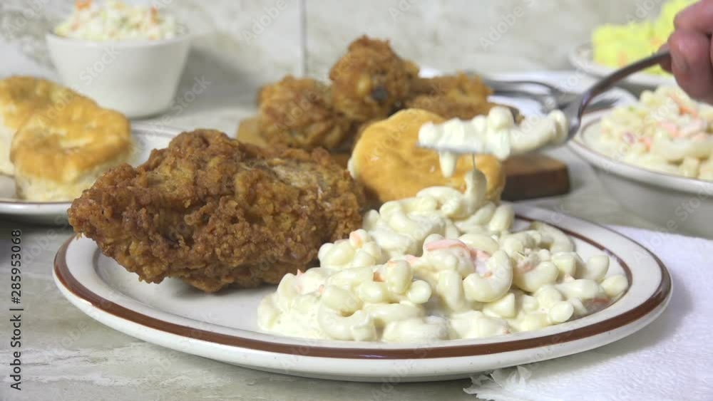 Eating a forkful of macaroni salad on a chicken dinner plate Eating a forkful of macaroni salad on a chicken dinner plate