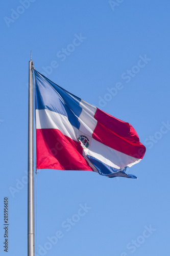 Flag of Dominican Republic (DR) waving in the wind with blue sky on background
