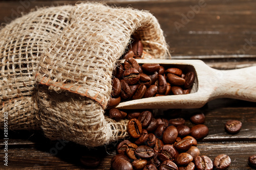 Coffee beans in hemp bag on a brown wood background