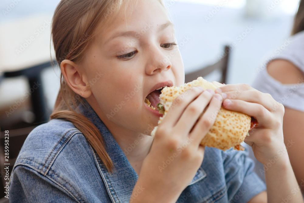 Girls Teenagers at a table in a cafe eat sandwiches and drink soda. Girls Teenagers at a table in a cafe eat sandwiches and drink soda.