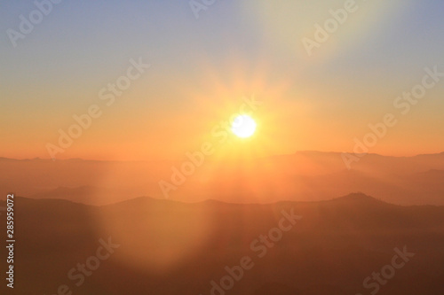 Beautiful golden natural sunlight and twiligh of sunrise shining to in the mist on valley of mountain in Thailand