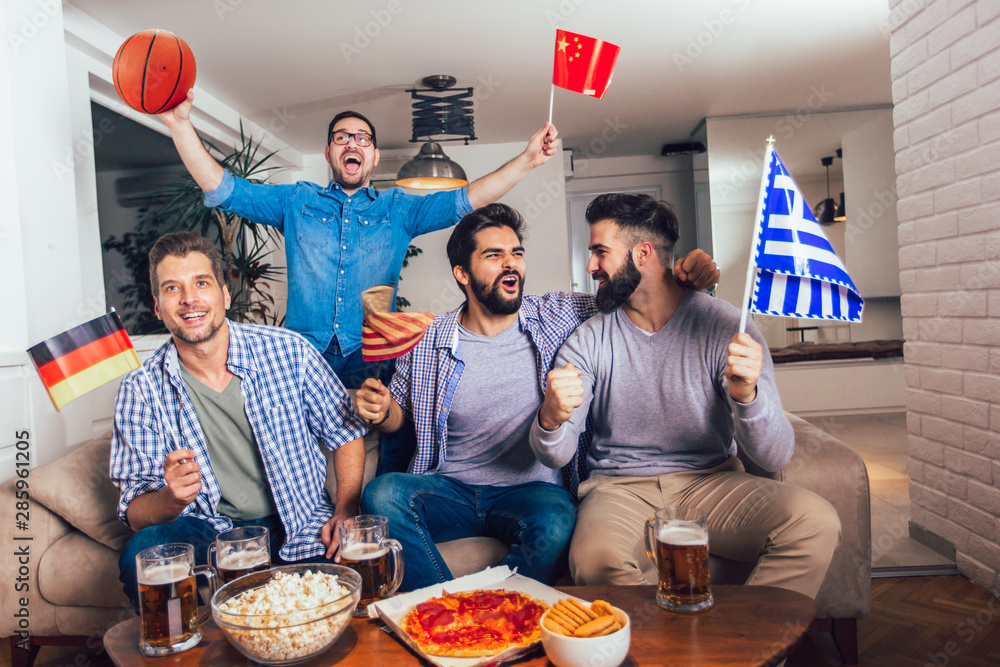 Happy friends or basketball fans watching basketball game on tv and celebrating victory at home.Friendship, sports and entertainment concept.