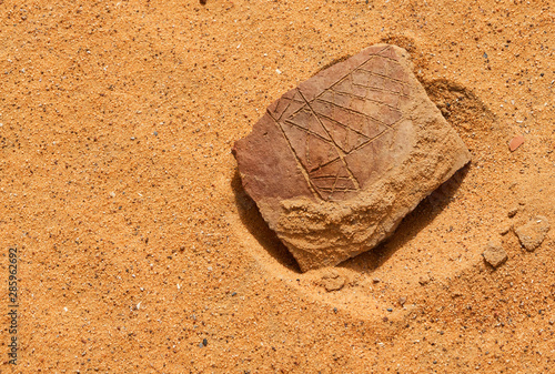 Shard of pottery found by chance in the Sudan desert with engraved antique symbols photo