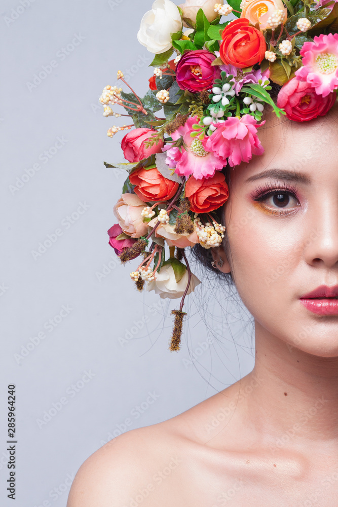 Close up of beautiful young asian woman with flowers. Brunette woman with luxury makeup. Perfect skin. Eyelashes. Cosmetic eyeshadow.