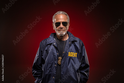 Detective wearing badge around his neck and sunglasses showing up for another day at work, catching criminals.