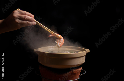 Hand holding chopsticks with shrimp over hot pot, Thai style, Barbecue Buffet with smoke