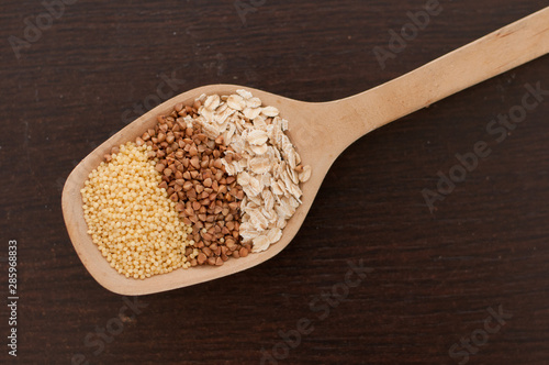 oatmeal, millet, buckwheat in a wooden spoon close-up on the table
