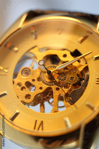 Beautiful luxury golden mechanical watch with white arrows close-up on a white blurred background. Clock face. Men's Watch. Transparent watch. Time. Clockwork. Selective focus.