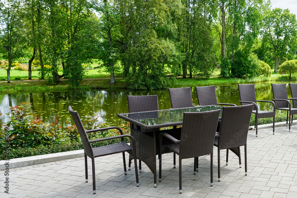Obraz premium empty restaurant with brown chairs by the beautiful pond in summer
